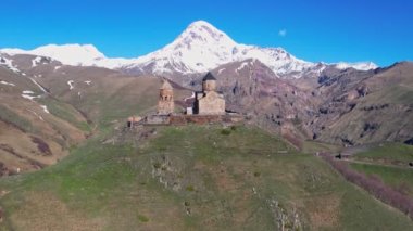 Gergeti Trinity Kilisesi 'nin, dağın üzerinden ağır sis bulutları akan hava aracı görüntüsü. Stepantsminda, Georgia yakınlarındaki karlı zirvelerin güzel dağ manzarası..