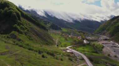 Yoğun sis bulutlarının dağın üzerinden uçuşunu gösteren hava aracı görüntüsü. Dağlarda asılı duran sisli bulutlar. Gürcistan, Gudauri yakınlarındaki karlı zirvelerin güzel dağ manzarası.