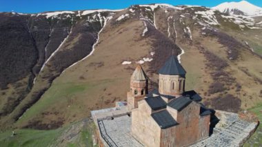 Gergeti Trinity Kilisesi 'nin, dağın üzerinden ağır sis bulutları akan hava aracı görüntüsü. Stepantsminda, Georgia yakınlarındaki karlı zirvelerin güzel dağ manzarası..