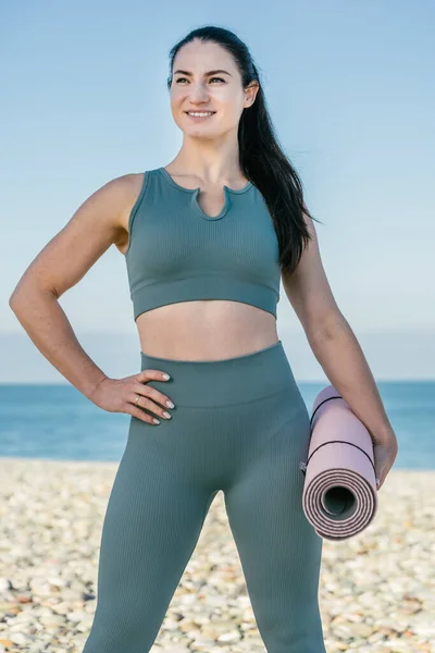 Sportif Güler Yüzlü Spor Giyim Koçu Yoga Minderini Tutuyor Plajda — Stok fotoğraf