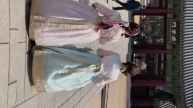 Güney Kore, Seul 'deki Changgyeonggung Sarayı' nda geleneksel Hanbok elbiseleri giyen Asyalı kadınlar. Dikey video. Seul, Güney Kore - 22 Mart 2023.