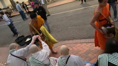 Geleneksel kutsal sadaka verme töreninde ellerinde sadaka kasesi olan rahipler. Yerel halk ve turistler, Luang Prabang, Laos 'taki Budist rahiplerin kaselerine yemek sundular. Vientiane, Laos - Mart 04, 2023.