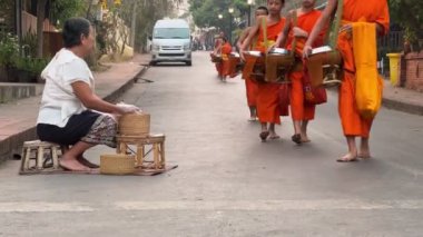 Geleneksel kutsal sadaka verme töreninde ellerinde sadaka kasesi olan rahipler. Yerel halk ve turistler, Luang Prabang, Laos 'taki Budist rahiplerin kaselerine yemek sundular. Vientiane, Laos - Mart 04, 2023.