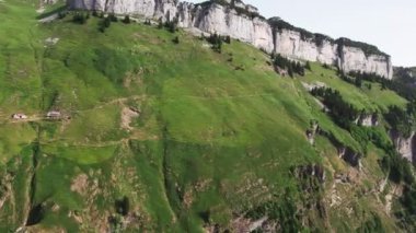 Aerial view of a mountainous landscape in Seealpsee, Switzerland. Drone footage of rocky Schafler Mountain and Seealpsee Lake under bright sunlight.