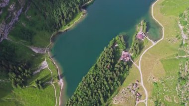Aerial view of a mountainous landscape in Seealpsee, Switzerland. Drone footage of rocky Schafler Mountain and Seealpsee Lake under bright sunlight.