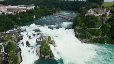 Rhine Şelaleleri ve Neuhausen am Rheinfall, İsviçre 'deki demiryolu köprüsü üzerinde uçuş. Doğal Ren Şelalesinin Nehirdeki Havadan Güzel Çekimi, Evlerin Üzerinde Uçan İnsansız Hava Aracı - Schaffhausen, İsviçre.