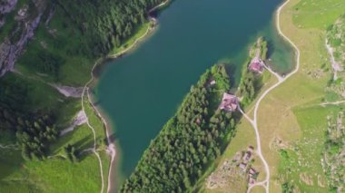 Aerial view of a mountainous landscape in Seealpsee, Switzerland. Drone footage of rocky Schafler Mountain and Seealpsee Lake under bright sunlight.