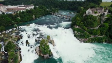 Rhine Şelaleleri ve Neuhausen am Rheinfall, İsviçre 'deki demiryolu köprüsü üzerinde uçuş. Doğal Ren Şelalesinin Nehirdeki Havadan Güzel Çekimi, Evlerin Üzerinde Uçan İnsansız Hava Aracı - Schaffhausen, İsviçre.