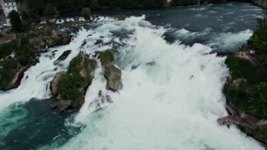 Rhine Şelaleleri ve Neuhausen am Rheinfall, İsviçre 'deki demiryolu köprüsü üzerinde uçuş. Doğal Ren Şelalesinin Nehirdeki Havadan Güzel Çekimi, Evlerin Üzerinde Uçan İnsansız Hava Aracı - Schaffhausen, İsviçre.