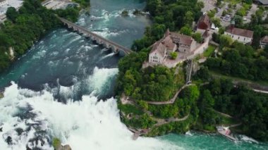 Rhine Şelaleleri ve Neuhausen am Rheinfall, İsviçre 'deki demiryolu köprüsü üzerinde uçuş. Doğal Ren Şelalesinin Nehirdeki Havadan Güzel Çekimi, Evlerin Üzerinde Uçan İnsansız Hava Aracı - Schaffhausen, İsviçre.