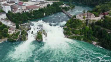 Rhine Şelaleleri ve Neuhausen am Rheinfall, İsviçre 'deki demiryolu köprüsü üzerinde uçuş. Doğal Ren Şelalesinin Nehirdeki Havadan Güzel Çekimi, Evlerin Üzerinde Uçan İnsansız Hava Aracı - Schaffhausen, İsviçre.