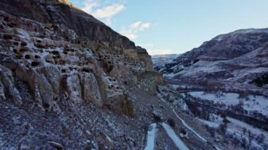 Ünlü ortaçağ mağara kenti manastırı Vardzia Erusheti Dağı 'nın yamaçlarından kazıldı. Kışın insansız hava aracıyla vurulmuş. Şehir karla kaplı. 4K görüntü. 