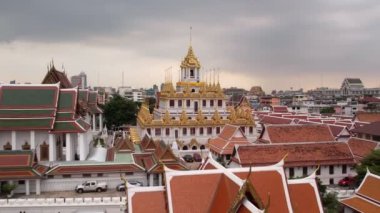 Bangkok Tayland 'daki Wat Ratchanatdaram Worawihan tapınağının havadan görünüşü. İkonik Loha Prasat 'ın çarpıcı görüntüleriyle tapınak, karmaşık kuleler ve zengin mimari güzelliği yavaş çekimde sıcak 4K