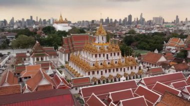 Bangkok Tayland 'daki Wat Ratchanatdaram Worawihan tapınağının havadan görünüşü. İkonik Loha Prasat 'ın çarpıcı görüntüleriyle tapınak, karmaşık kuleler ve zengin mimari güzelliği yavaş çekimde sıcak 4K