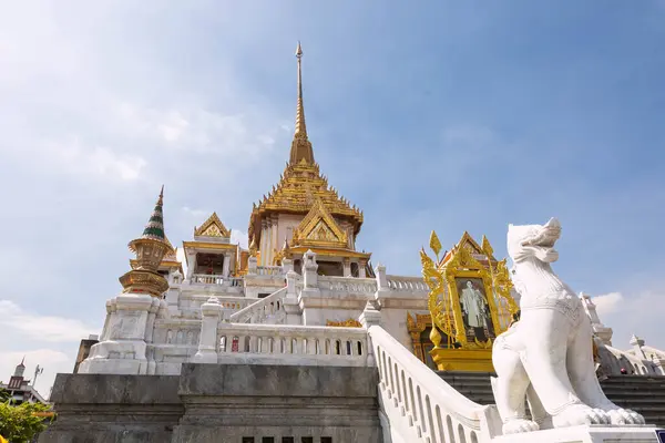 stock image Wat Traimit temple against the sky: made of white marble and gold, with a pointed spire and adorned with sculptures, Bangkok, Thailand