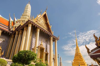 Ana Wat Phra Kaew tapınağına giriş, altın ve karmaşık desenlerle bezenmiş, güneşli bir günde mavi bir gökyüzüne karşı, Bangkok, Tayland.