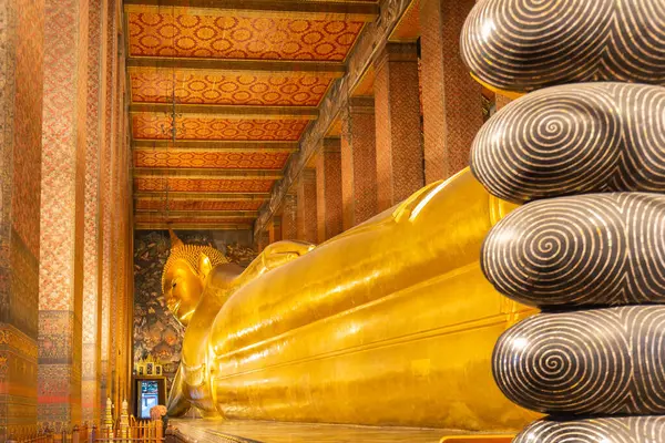 stock image Large gilded sculpture of the Reclining Buddha at the richly decorated mosaic Wat Pho temple, with fingers prominently visible in the foreground, Bangkok, Thailand