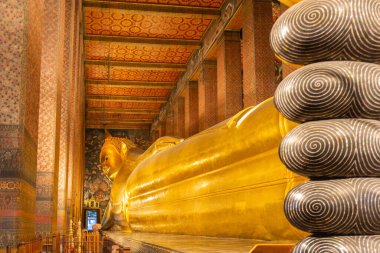 Zengin dekore edilmiş Wat Pho tapınağındaki uzanan Buda heykelinin ön planda belirgin parmakları olan Bangkok, Tayland