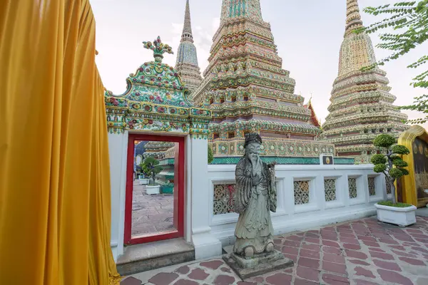 stock image Temple of the Reclining Buddha Wat Pho, richly adorned with mosaic, with statue at the gates, Bangkok, Thailand