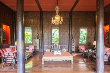 Ahşap duvarlar, sütunlar ve mobilyalarla dekore edilmiş güzel bir geleneksel Tayland iç mimarisi, bir avize, oturma alanı, ve Jim Thompson Evi, Bangkok, Tayland 'da Buda heykeli