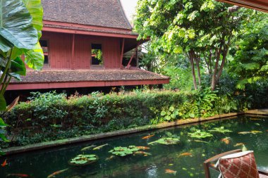 Bangkok, Tayland 'daki Jim Thompsons' ların evinde yemyeşil ve geleneksel Tayland mimarisi ile çevrili bir koi göleti, sakin bir atmosfer yaratıyor.