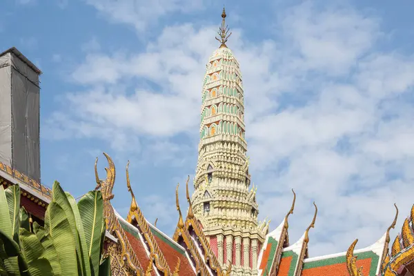 stock image Decorated towers and roofs of Wat Arun against a blue sky, with a guardian sculpture in the foreground, Bangkok, Thailand.