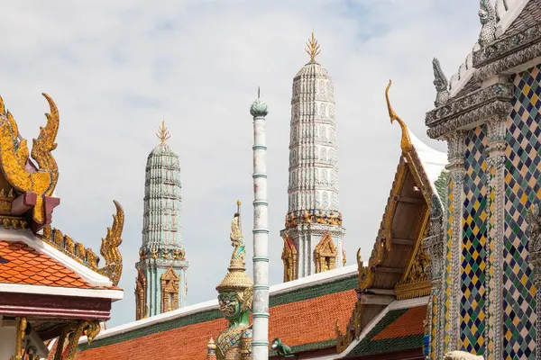 stock image Ornately decorated towers and roofs of Wat Arun against a blue sky, with a guardian sculpture in the foreground, Bangkok, Thailand