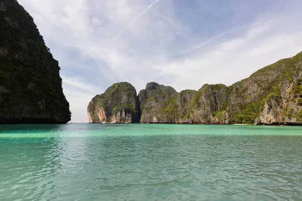 Tayland 'ın Phi Phi Ley Adası' ndaki Maya Körfezi 'nde berrak bir gökyüzü altında yemyeşil sularla kaplı yüksek kireçtaşı kayalıkları bulunuyor.