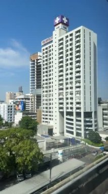 Bangkoks şehir manzarası, yeşil, kentsel gelişim ve modern mimari ile çevrili konut ve ticari yapıların karışımı ile berrak mavi gökyüzü altında yüksek binalar içerir..