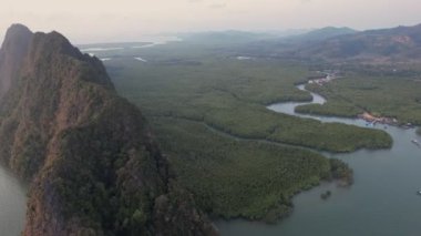 Sakin sularla çevrili yemyeşil adalar ve uzak yüksek kaya oluşumları Samet Nangshe bakış açısıyla sakin ve resimli bir manzara yaratır..