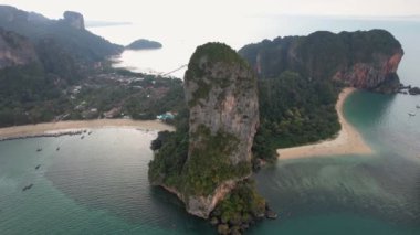 Tayland 'ın Krabi kentindeki ünlü Railay Sahili' ni çevreleyen çarpıcı kireçtaşı kayalıkların havadan görünüşü, kıyı boyunca uzun kuyruklu tekneler ve manzaralı plajın keyfini çıkaran turistler.. 