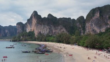 Tayland 'ın Krabi kentindeki ünlü Railay Sahili' ni çevreleyen çarpıcı kireçtaşı kayalıkların havadan görünüşü, kıyı boyunca uzun kuyruklu tekneler ve manzaralı plajın keyfini çıkaran turistler.. 