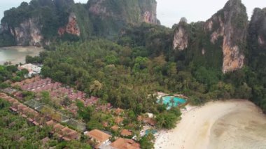 Tayland 'ın Krabi kentindeki ünlü Railay Sahili' ni çevreleyen çarpıcı kireçtaşı kayalıkların havadan görünüşü, kıyı boyunca uzun kuyruklu tekneler ve manzaralı plajın keyfini çıkaran turistler.. 