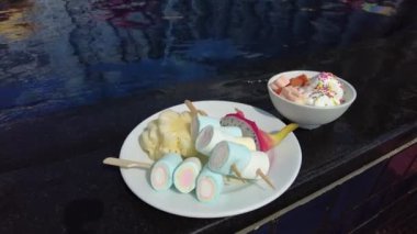 Bir tabak renkli atıştırmalık ve havuz kenarında serpiştirilmiş bir kase dondurma rahatlatıcı ve hoşgörülü bir tatil anını yansıtır..