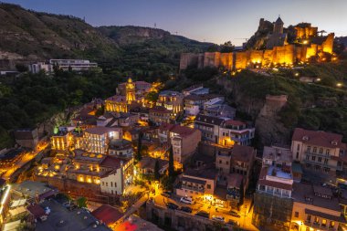 Tiflis 'in gece aydınlanması Narikala kalesi ve Gürcistan' ın eski Tiflis kasabasının insansız hava aracı gözünden. Gün batımında Tiflis 'in güzel panoramik manzarası.