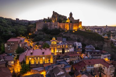 Tiflis 'in gece aydınlanması Narikala kalesi ve Gürcistan' ın eski Tiflis kasabasının insansız hava aracı gözünden. Gün batımında Tiflis 'in güzel panoramik manzarası.