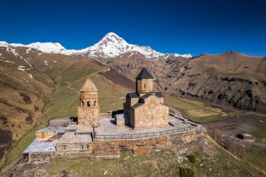Gergeti Trinity Kilisesi 'nin, dağın üzerinden ağır sis bulutları akan hava aracı görüntüsü. Stepantsminda, Georgia yakınlarındaki karlı zirvelerin güzel dağ manzarası..