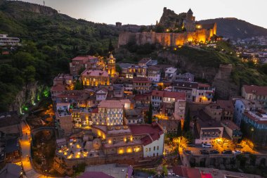 Tiflis 'in gece aydınlanması Narikala kalesi ve Gürcistan' ın eski Tiflis kasabasının insansız hava aracı gözünden. Gün batımında Tiflis 'in güzel panoramik manzarası.