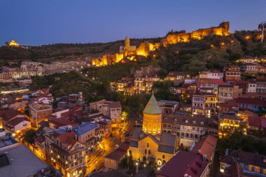 Tiflis 'in gece aydınlanması Narikala kalesi ve Gürcistan' ın eski Tiflis kasabasının insansız hava aracı gözünden. Gün batımında Tiflis 'in güzel panoramik manzarası.