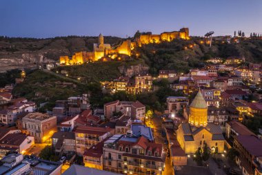 Tiflis 'in gece aydınlanması Narikala kalesi ve Gürcistan' ın eski Tiflis kasabasının insansız hava aracı gözünden. Gün batımında Tiflis 'in güzel panoramik manzarası.