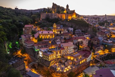 Tiflis 'in gece aydınlanması Narikala kalesi ve Gürcistan' ın eski Tiflis kasabasının insansız hava aracı gözünden. Gün batımında Tiflis 'in güzel panoramik manzarası.