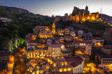 Tiflis 'in gece aydınlanması Narikala kalesi ve Gürcistan' ın eski Tiflis kasabasının insansız hava aracı gözünden. Gün batımında Tiflis 'in güzel panoramik manzarası.