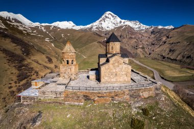 Gergeti Trinity Kilisesi 'nin, dağın üzerinden ağır sis bulutları akan hava aracı görüntüsü. Stepantsminda, Georgia yakınlarındaki karlı zirvelerin güzel dağ manzarası..