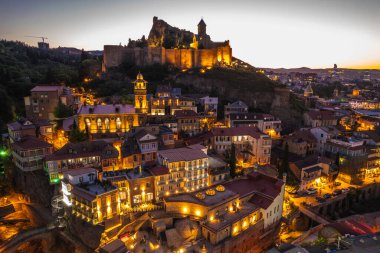 Tiflis 'in gece aydınlanması Narikala kalesi ve Gürcistan' ın eski Tiflis kasabasının insansız hava aracı gözünden. Gün batımında Tiflis 'in güzel panoramik manzarası.