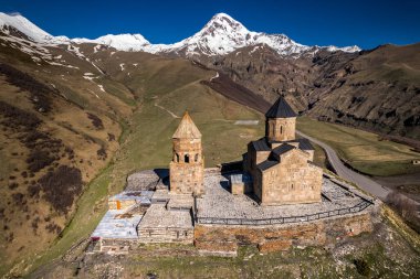 Gergeti Trinity Kilisesi 'nin, dağın üzerinden ağır sis bulutları akan hava aracı görüntüsü. Stepantsminda, Georgia yakınlarındaki karlı zirvelerin güzel dağ manzarası..