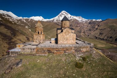Gergeti Trinity Kilisesi 'nin, dağın üzerinden ağır sis bulutları akan hava aracı görüntüsü. Stepantsminda, Georgia yakınlarındaki karlı zirvelerin güzel dağ manzarası..