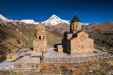 Gergeti Trinity Kilisesi 'nin, dağın üzerinden ağır sis bulutları akan hava aracı görüntüsü. Stepantsminda, Georgia yakınlarındaki karlı zirvelerin güzel dağ manzarası..