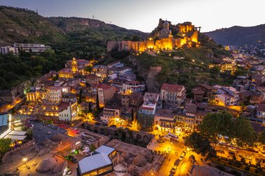 Tiflis 'in gece aydınlanması Narikala kalesi ve Gürcistan' ın eski Tiflis kasabasının insansız hava aracı gözünden. Gün batımında Tiflis 'in güzel panoramik manzarası.