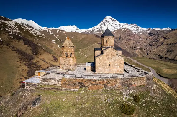 Gergeti Trinity Kilisesi 'nin, dağın üzerinden ağır sis bulutları akan hava aracı görüntüsü. Stepantsminda, Georgia yakınlarındaki karlı zirvelerin güzel dağ manzarası..