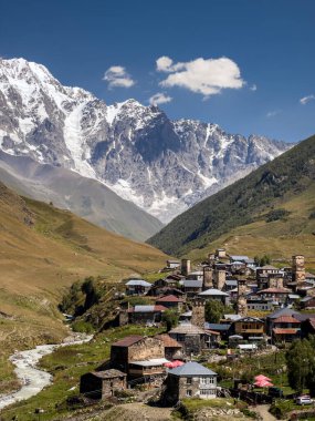 Ortaçağ taş kuleleri ve Georgias Kafkasya bölgesindeki karlı dağlar ve yemyeşil tepelerle dolu vadide yuva yapmış Ushguli köyünün manzarası..